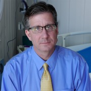 Dark-haired man with glasses in a doctor's exam room